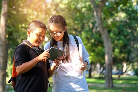 Asian students boy and girl playing tablet in the park.の写真素材