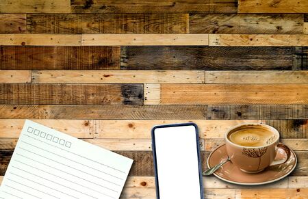 Smart phone and note paper with coffee cup on wooden pallets background.の写真素材