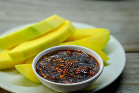 Mango and sweet sauce in white dish on wooden floor.の写真素材