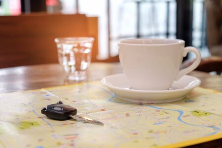 Coffee and car key place on the map with glass water on table.の写真素材