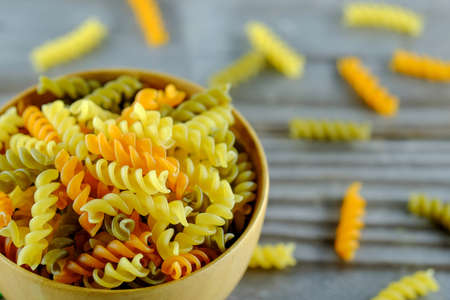 Spiral pasta in a wooden cup place on wooden floor.の写真素材