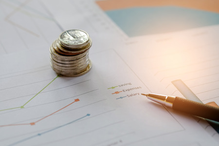 Concept businness,Coins and pen placed on the graph.