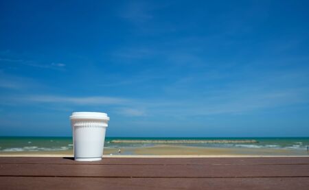 Take away coffee on wooden floor with sea background.の写真素材