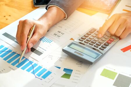 Businessman analyzes graph data and use the calculator to calculate the cost.