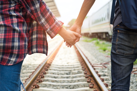 Male and female tourists walking hand in hand on railway tracks.の写真素材
