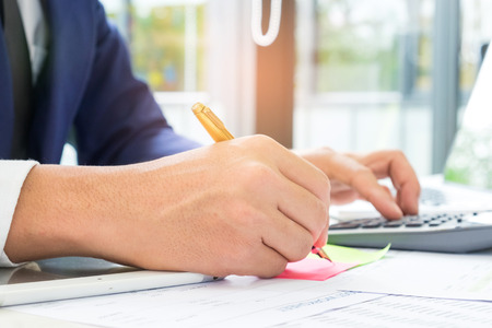 Business concepts,Office worker is using a calculator and taking notes in a flip chart,Business people are taking notes on a flip chart and using a calculator.の写真素材