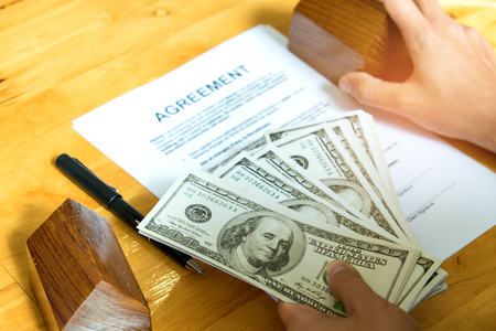 Home buying concept,Dollars and model houses with agreement documents on the table.の写真素材