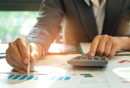 Businessmen are analyzing graphs and using calculator,Businessman has a pen in his hand, points to a graph and is using a calculator.の写真素材