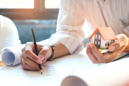 Architects are writing home,model house on other hand,Architects wear white shirts and mdel house with red roof.の写真素材