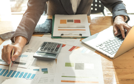 Business concepts,Men wearing suits are using a pen pointing on graph and another hand use laptop,Top view photo.の写真素材