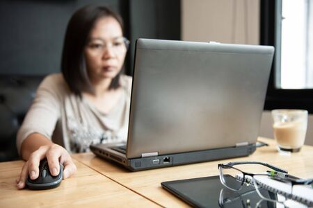 Asian girl office worker using laptop in office.Notebook and tablet on the desk.の写真素材