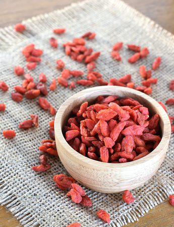 Goji in wooden cup place on sackcloth.の写真素材
