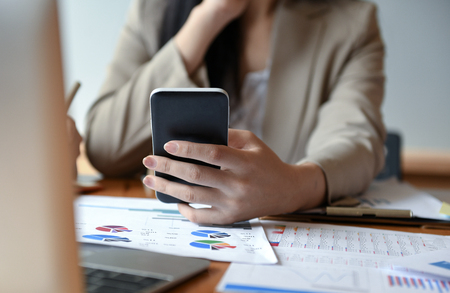 Employees are using smartphone and laptop place front,Pen and documents on the desk.の写真素材