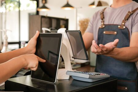 Barista is using the screen to receive orders from customers who are viewing the menu on the tablet.