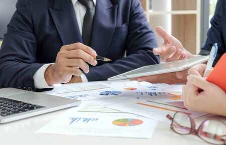 Management team and the secretary are meeting the work summary.Businessmen use tablet and laptop,...
