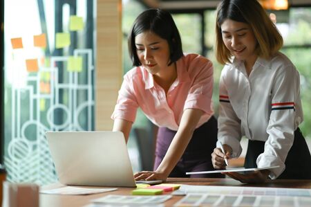 Asian female graphic designer working together at the office They use laptop and tablet.の写真素材