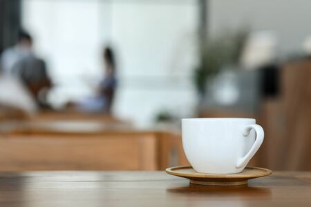 Coffee white mug on wooden floor in cafe.
