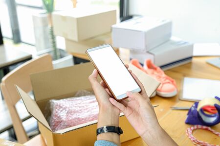 Online seller use mobile phone to take picture of products in box send to customer.の写真素材