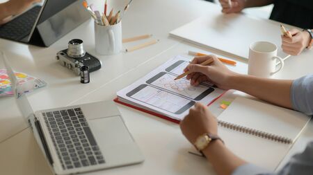 Cropped shot of young UX designer team working on smartphone application project with using digital tablet in modern office room.の写真素材