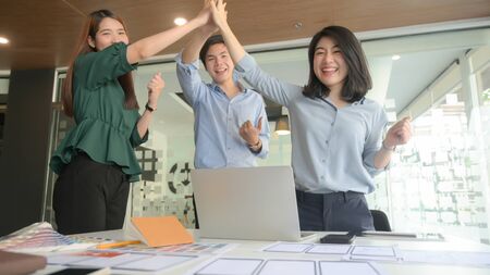 Business team raised their hands to show their joy after the meeting video conferencing with the...