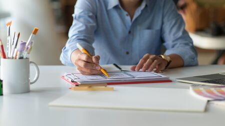 Cropped shot of Designer is sketching a smartphone screen for future customers on the desk with...