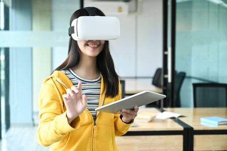 Cropped shot of a young female student wearing a VR glasses and using a laptop.の写真素材