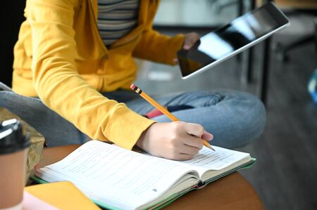 Cropped shot of a young female student taking notes and using a laptop, preparing for her entrance exam.の写真素材