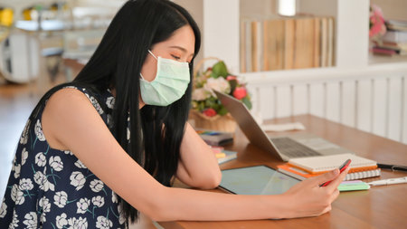 Young woman uses a tissue to cover her mouth and sneeze in a cafe.She is at risk of spreading the...