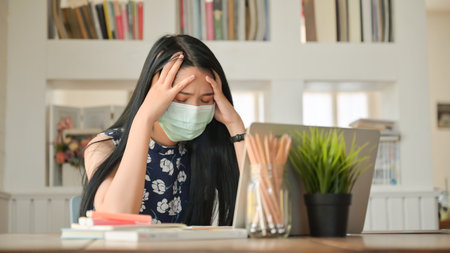 Young woman uses a tissue to cover her mouth and sneeze in a cafe.She is at risk of spreading the...