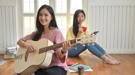Asian teenage girls are singing and playing guitars.They stay at home to prevent the corona virus outbreak.の写真素材