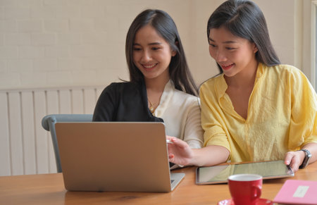 Two female college students use a laptop to study online at home to prevent the covid-19 virus outbreak.の写真素材