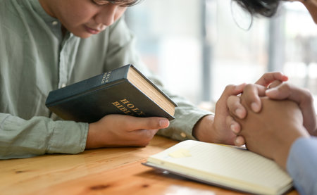 Close-up shot of The young man holding the bible and bowing to pray.の写真素材