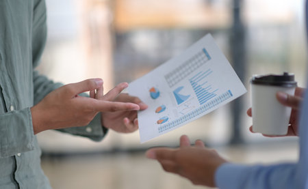 Cropped shot of Team freelance holding graphs and coffee in hand.