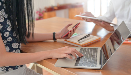 Close-up shot of A woman using a laptop and carrying a smartphone.の写真素材