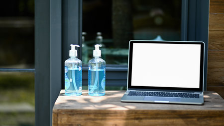 close - up shot of Mockup laptop blank screen with alcohol gel on a wooden table.の写真素材