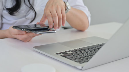 Close-up shot of Hand of woman places a smartphone on top to share a wireless charger while she is...