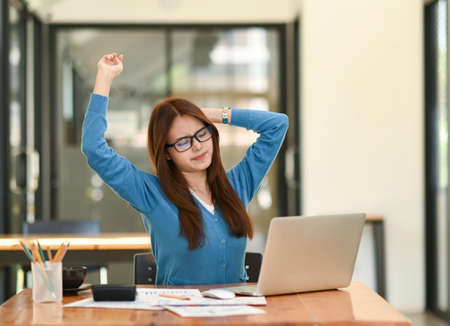 Asian woman in blue shirt stretching her arms to relax. During work in the office, office syndrome, business idea, office equipment.の写真素材
