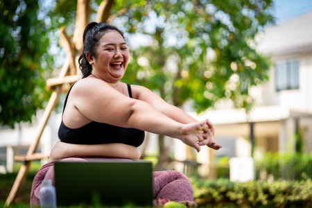 An obese woman who turns to exercise to take care of her health and lose weight on the lawn in a fun way.の写真素材