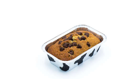 Homemade banana cake on top of semi-sweet chocolate chips in the metal form on white background. Top view.の写真素材
