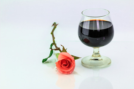 Pink rose and wine in glass on a white backgroundの写真素材