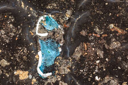 damaged shoes in waste asphalt