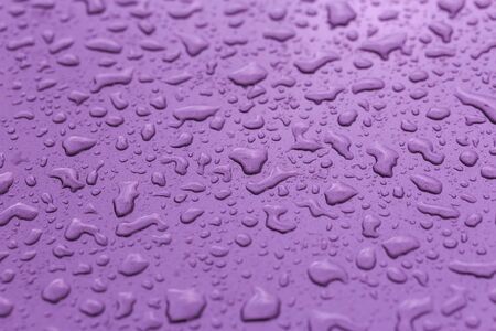 Drop water rain on the purple car in close up background and texturesの写真素材