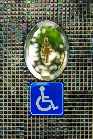 Wheelchair lady toilet signs on black square mosaic wallの写真素材