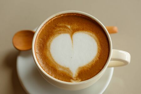 Heart shape in hot cappuccino coffee cup on white deskの写真素材