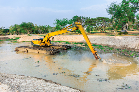CHONBURI , THAILAND - MARCH 16 ,2016 : The dirty backhoe working in mud lake, iron digger into water in the morning in Sattahip Chonburi, Thailand on March 16, 2016のeditorial素材