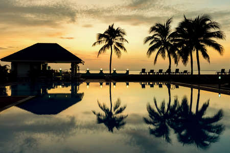 Silhouettes of the cocohut trees and gazebos in the morningの写真素材