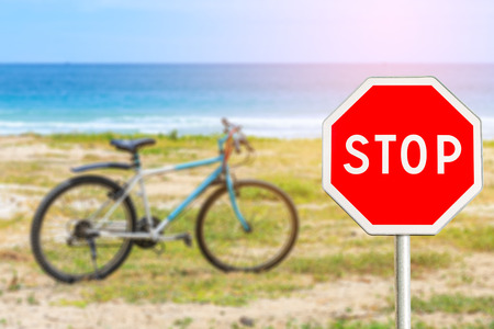 Stop sign by the sea and Parked bicycle on the beach in day timeの写真素材