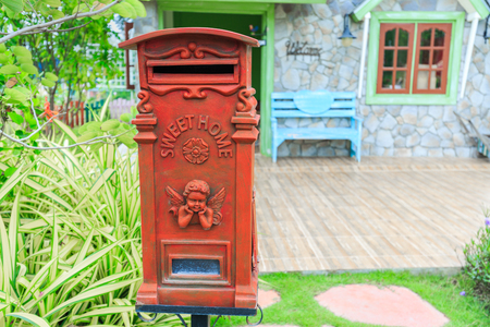 Red old-fashioned mailbox or vintage post box in front of House.の写真素材