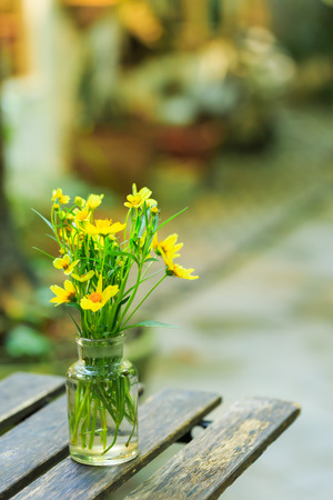 Marigold flower in vase on wooden tableの写真素材