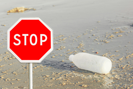 Red Stop sign on discarded water bottle laying on a beach background , save environment conceptの写真素材